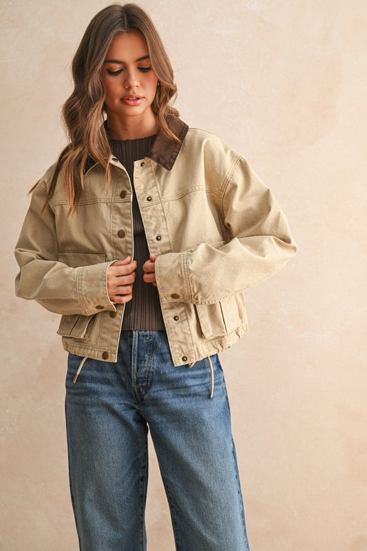 Woman wearing a beige jacket and blue jeans against a beige background