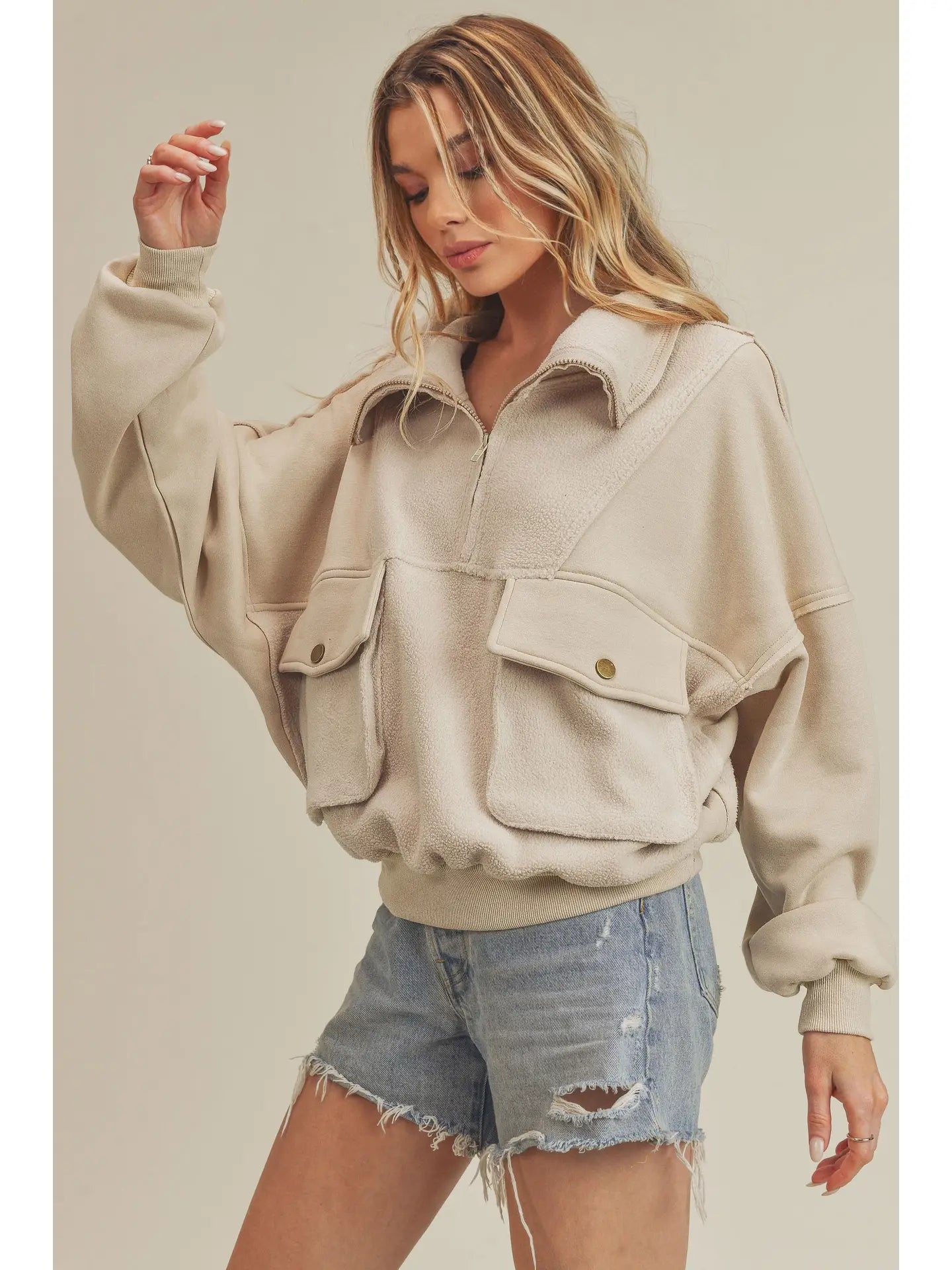 Woman wearing a beige jacket with pocket details on a plain background