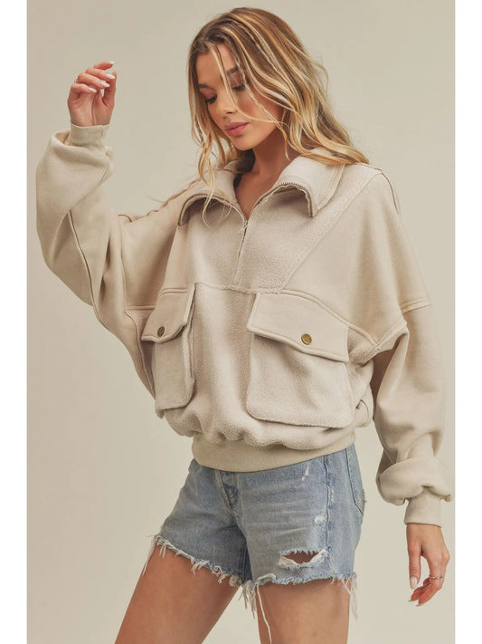Woman wearing a beige jacket with pocket details on a plain background