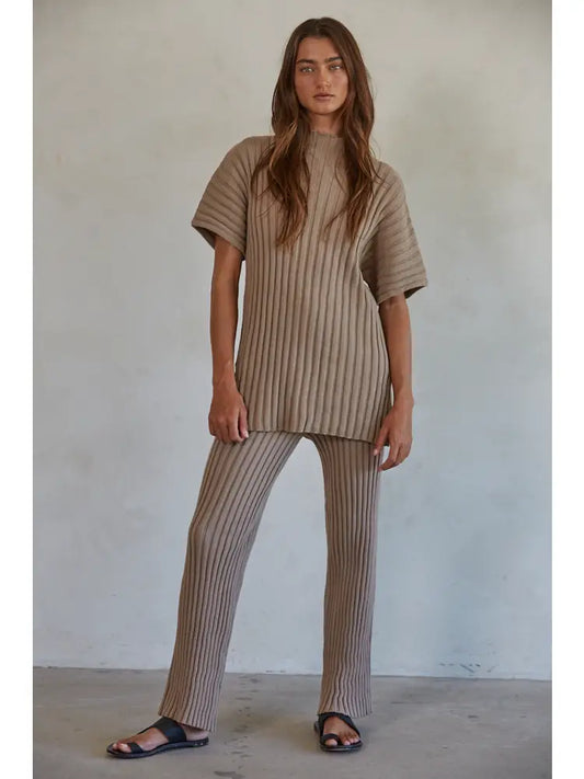 Woman wearing a beige ribbed outfit against a plain background